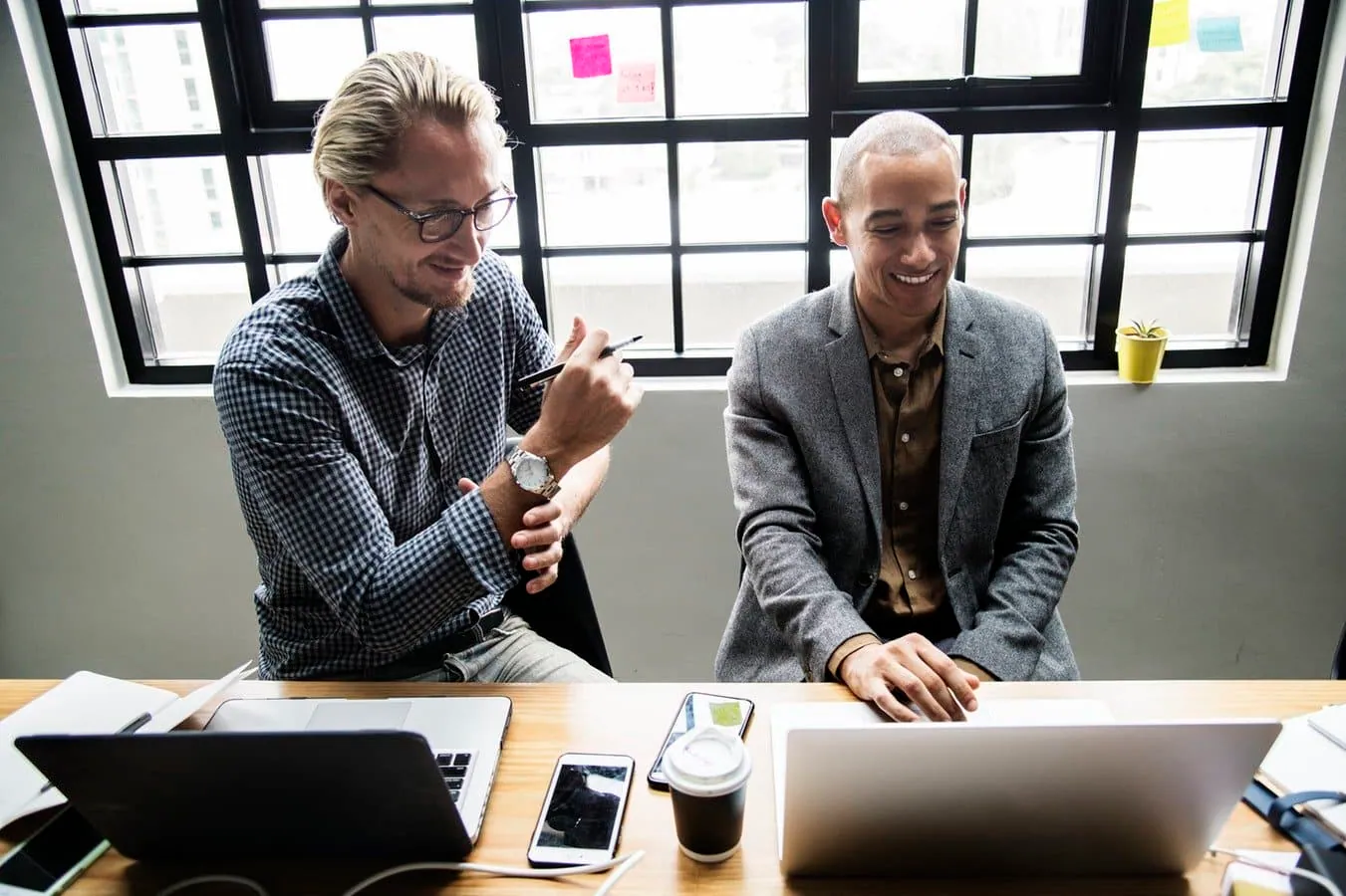 two male coworkers discussing technology support options over their laptops